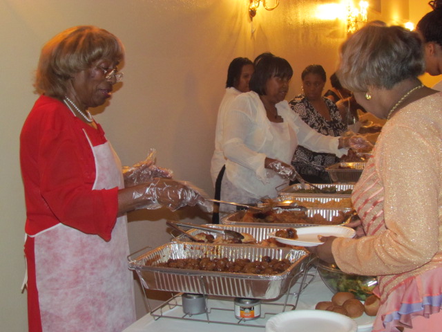Church members volunteering at a community event, serving food to families.