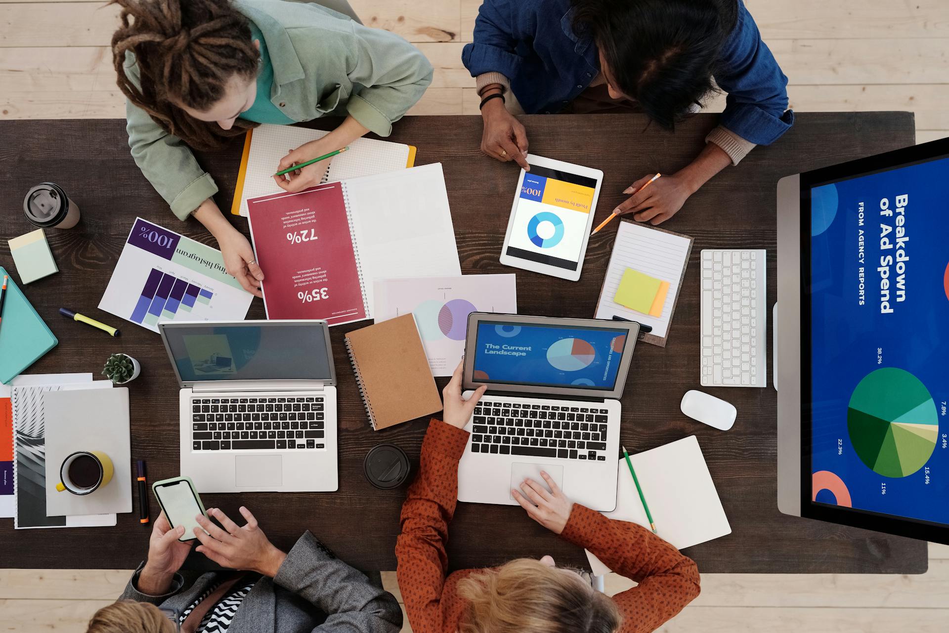 People working on laptops at a table, focused on the laptop screen.