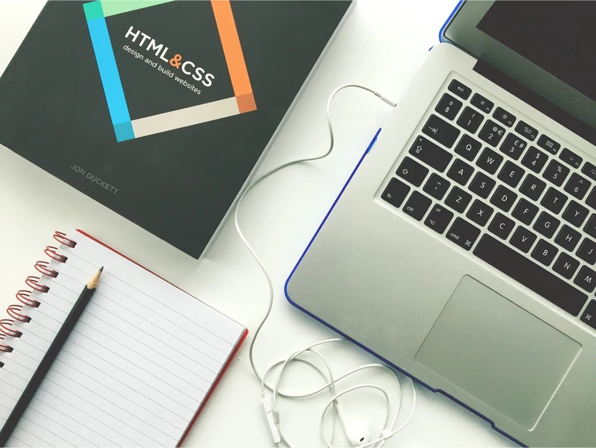 A image containing book of HTML & CSS, Laptop and a Notebook
