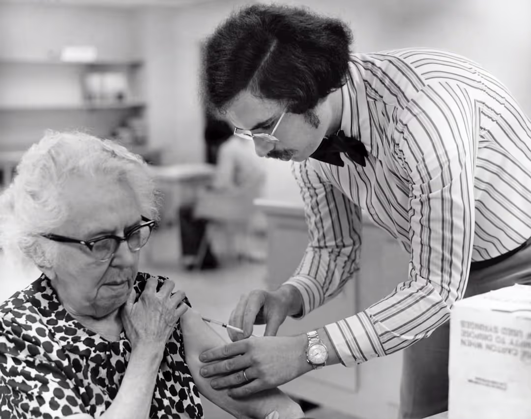 A kind nurse holding the hand of an elderly patient in a hospital bed