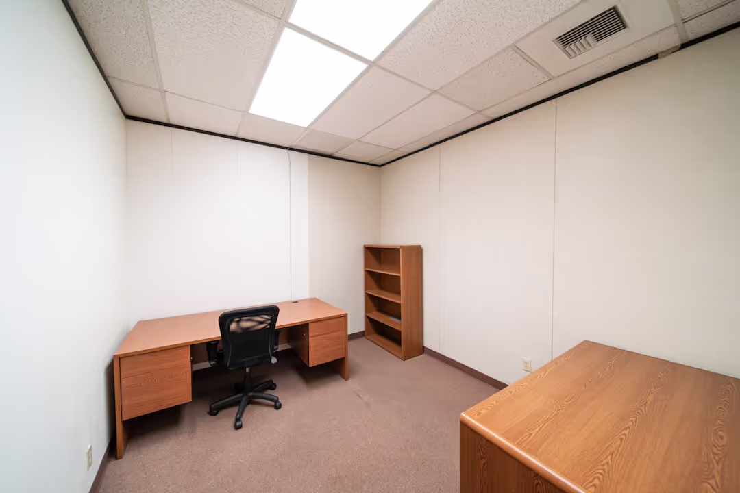 A clean and private consultation room with a doctor's desk and essential medical tools.