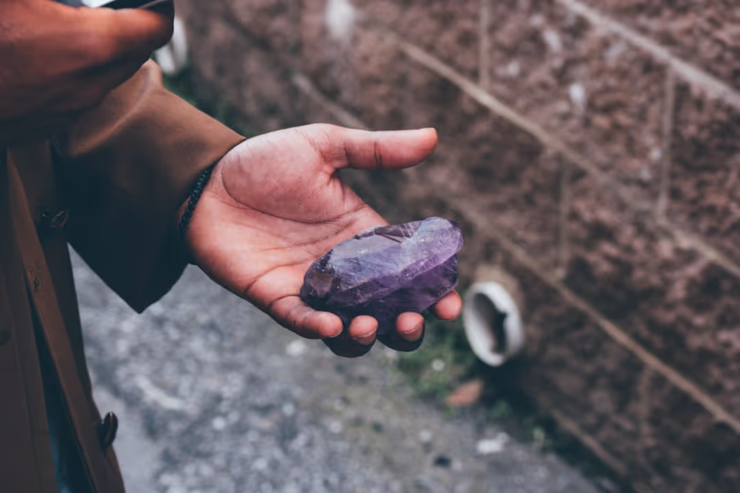 Close-up of hands holding a polished rock, symbolizing the healing journey and craft.