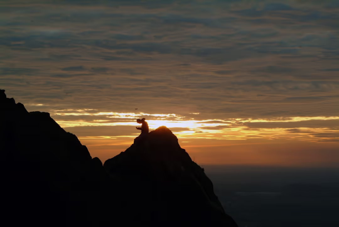 A person meditating on a mountain, symbolizing resilience and inner strength at sunrise