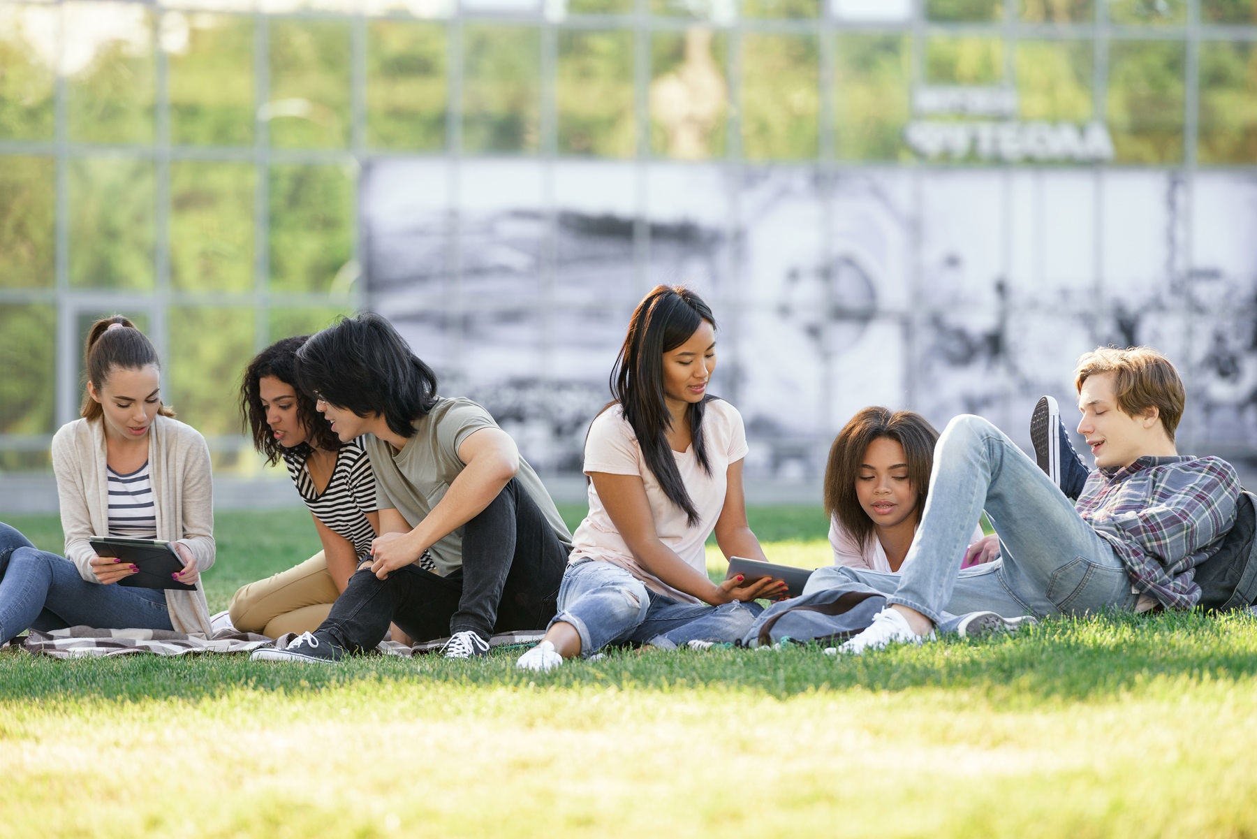 College students laughing together on the campus lawn, demonstrating social belonging, friendship, and practicing College belonging tips that work.