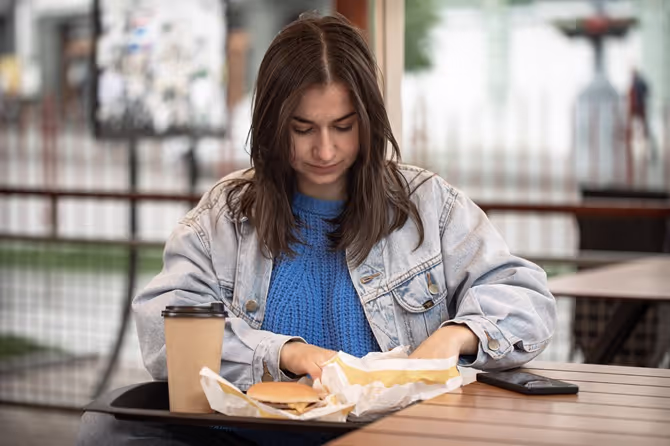 Student sitting alone in a dining hall, showing the need for College belonging tips that work.