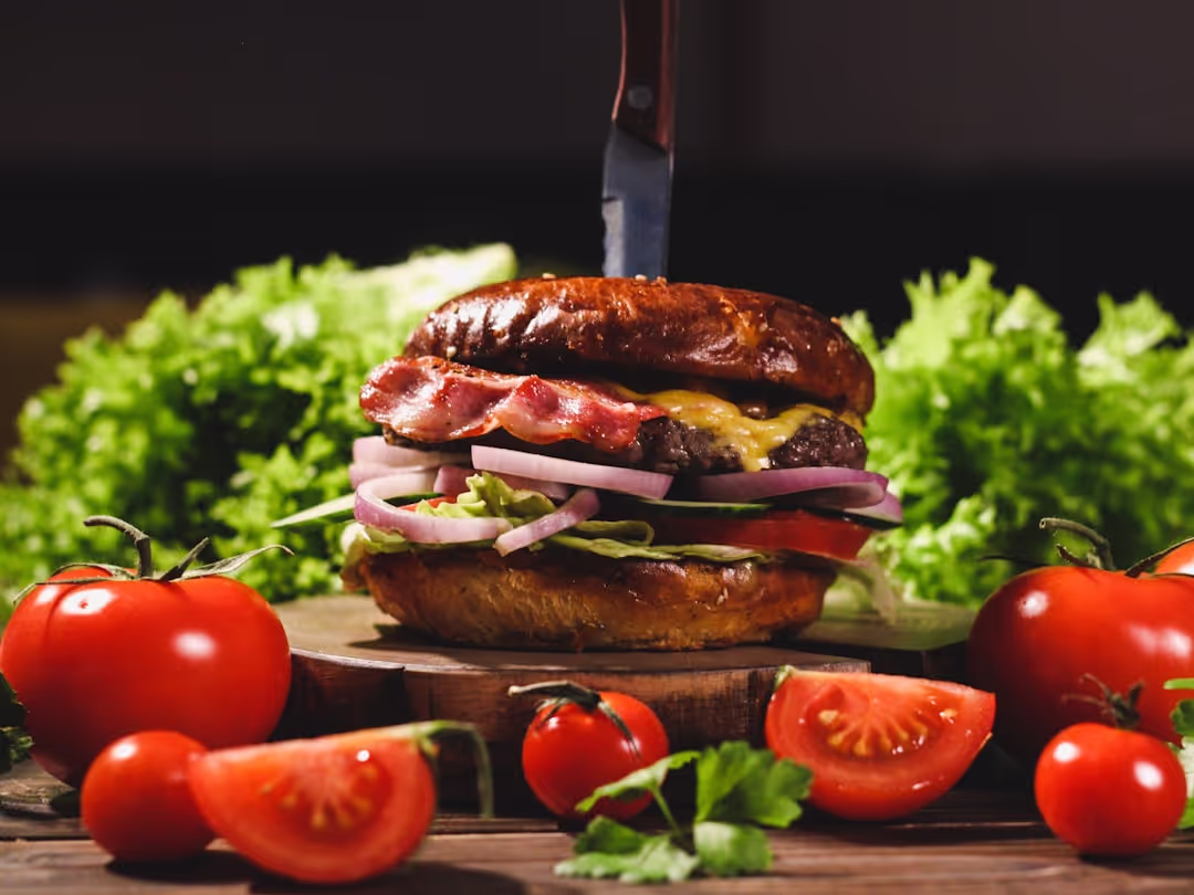 A classic hamburger with a thick patty, fresh lettuce, tomato, onion, and pickles, on a toasted bun.
