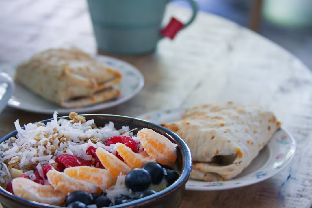A large breakfast burrito, cut in half, showcasing eggs, cheese, and sausage, on a white plate.