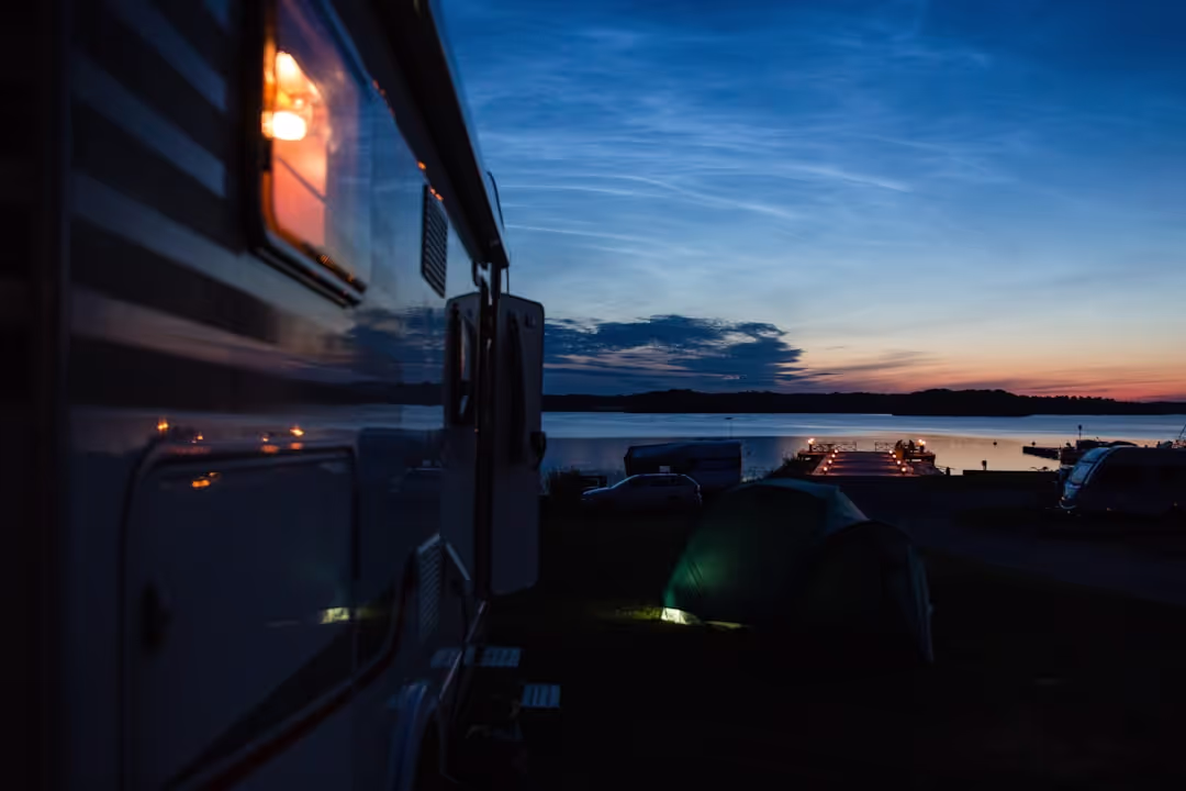 Red T4 camper van by a scenic European lake