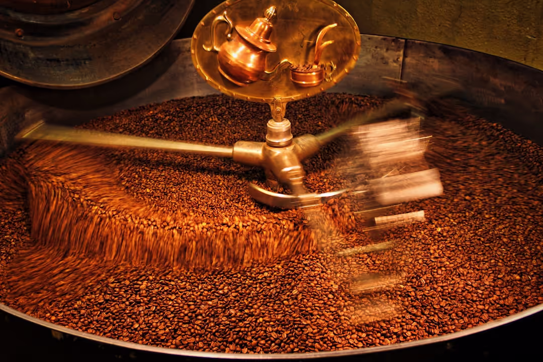 A close-up of coffee beans being meticulously ground in an antique-style manual grinder.