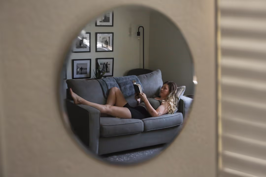 A person relaxing with a book and coffee in a cozy leather armchair, bathed in warm light.