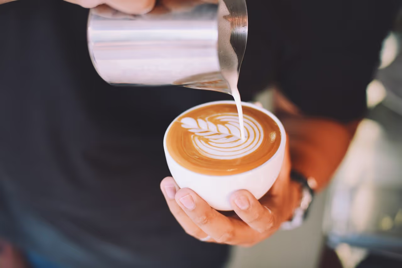 A hand holding a ceramic coffee mug by a crackling campfire at dawn, showing rustic charm.