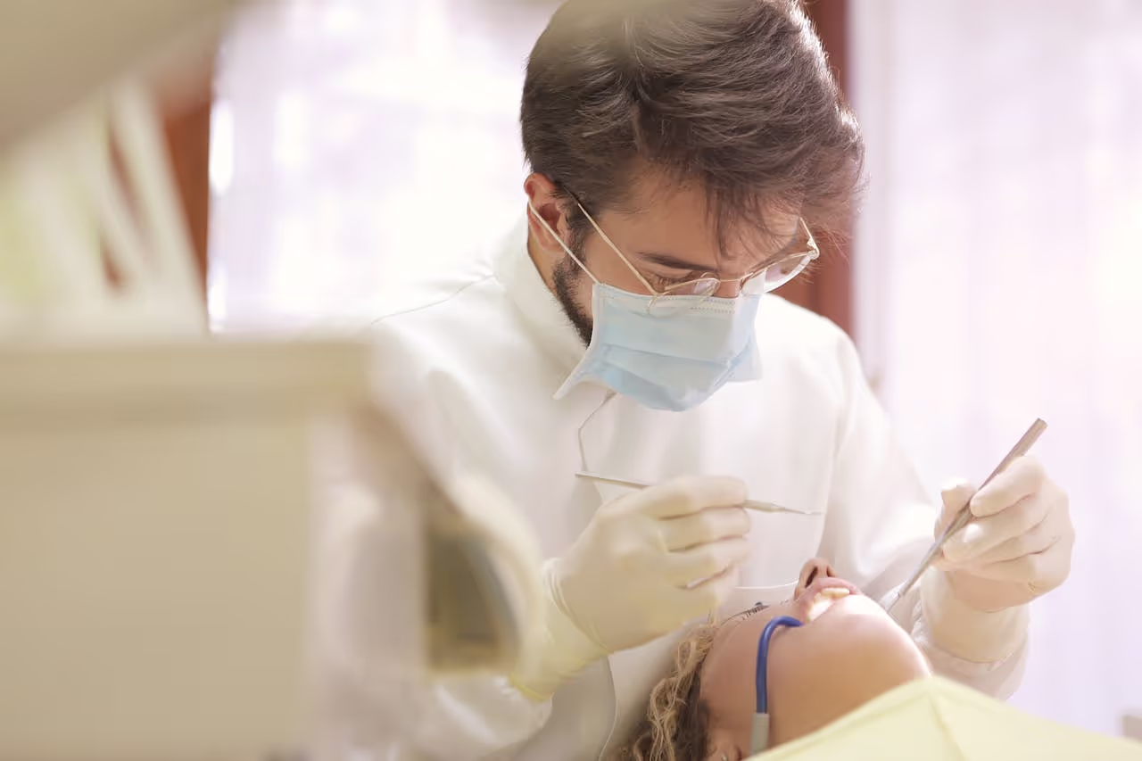 Dentist in face mask conducting a dental examination with tools in clinic setting