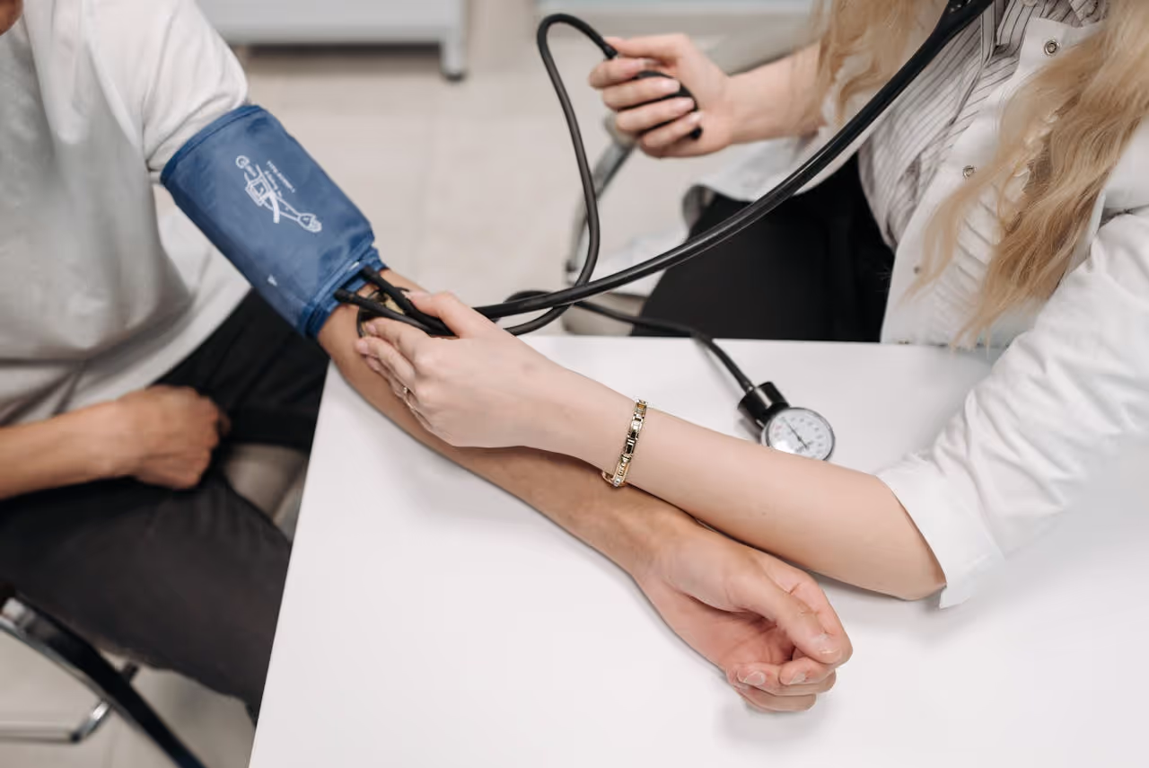 A doctor measures a patient's blood pressure with a sphygmomanometer during a consultation
