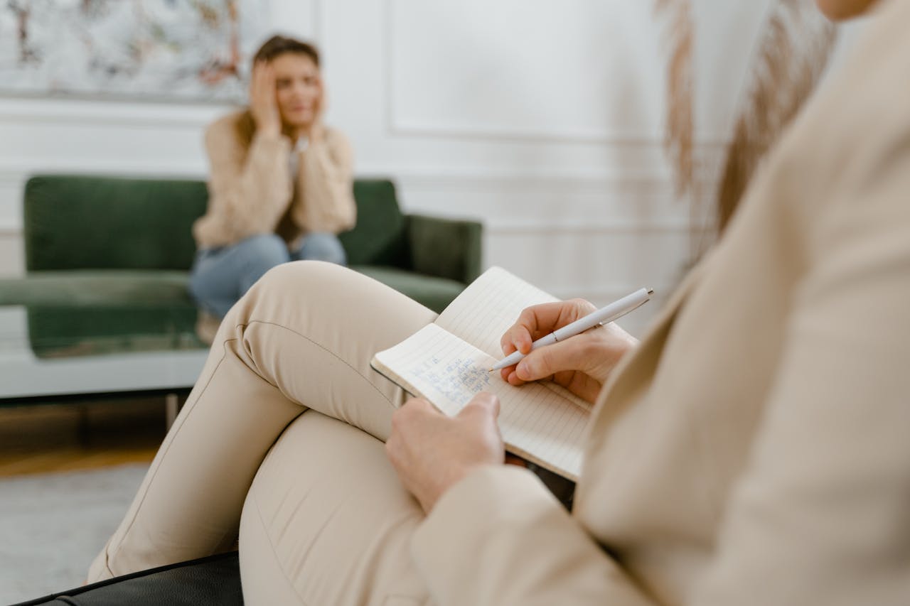 A therapist taking notes during a consultation with a patient focusing on mental health