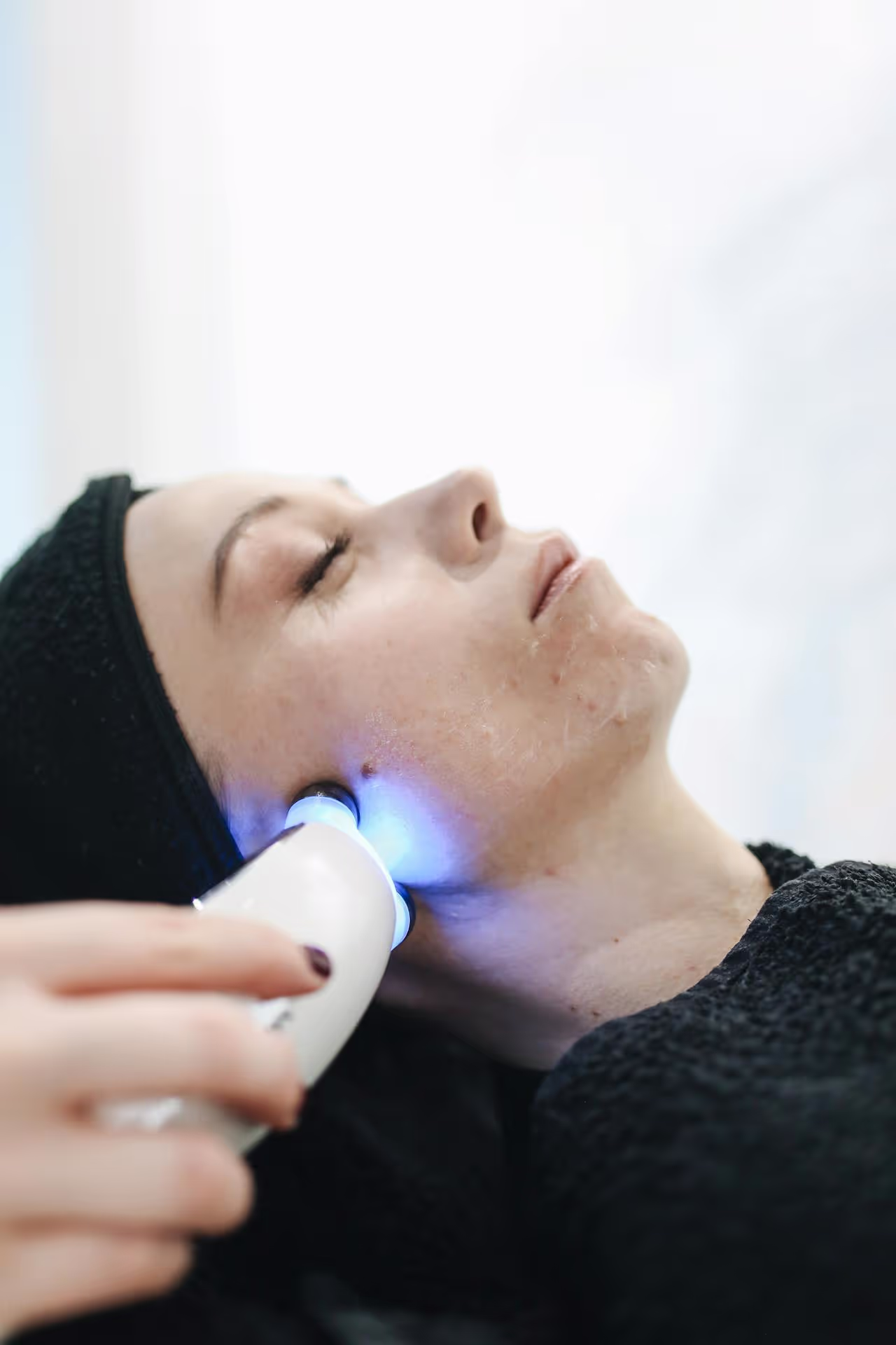 A woman enjoying a relaxing facial treatment with a skincare device at a spa
