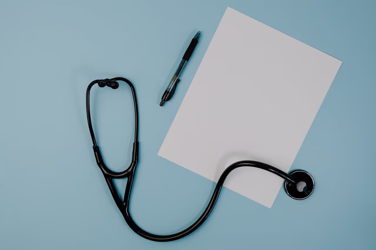 Close upFlat lay of stethoscope blank paper and pen on blue surface ideal for medical themes of diabetes management tools and educational materials on a table