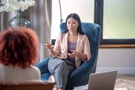 A therapist discusses with a patient in a bright sunlit room for a mental health session