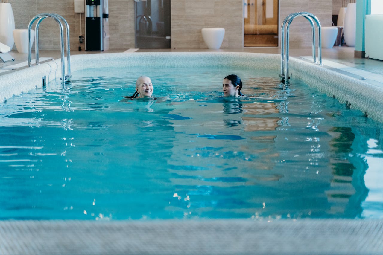 Senior woman and adult woman enjoying a relaxing swim in an indoor pool featuring leisure and relaxation